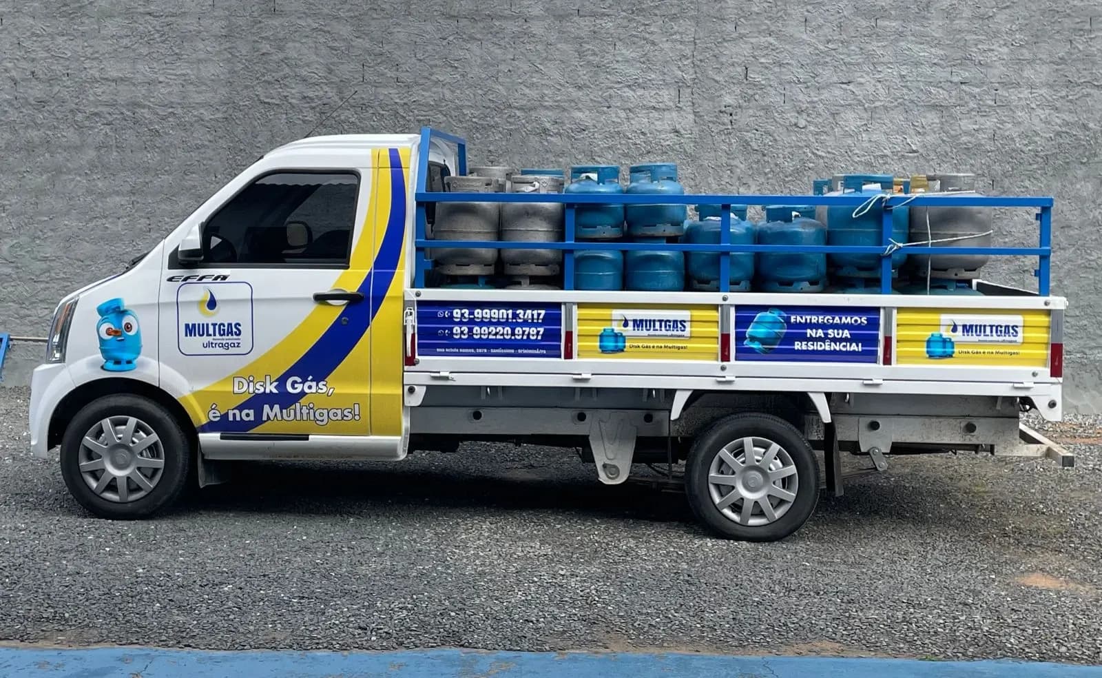 Picape V21 adesivada de uma distribuidora de gás, com a caçamba cheia de botijões