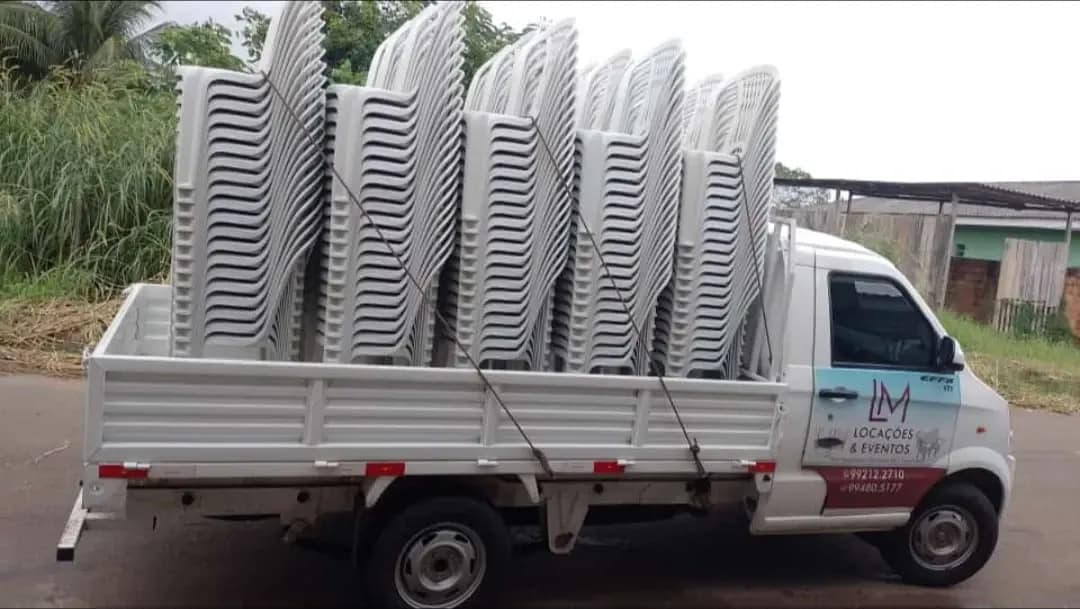 Picape V21 de uma empresa de locação levando pilhas de cadeiras plásticas