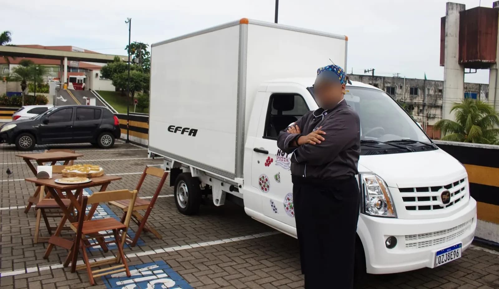 V21 Baú estacionado ao lado de mesas de um restaurante, com o cozinheiro em frente