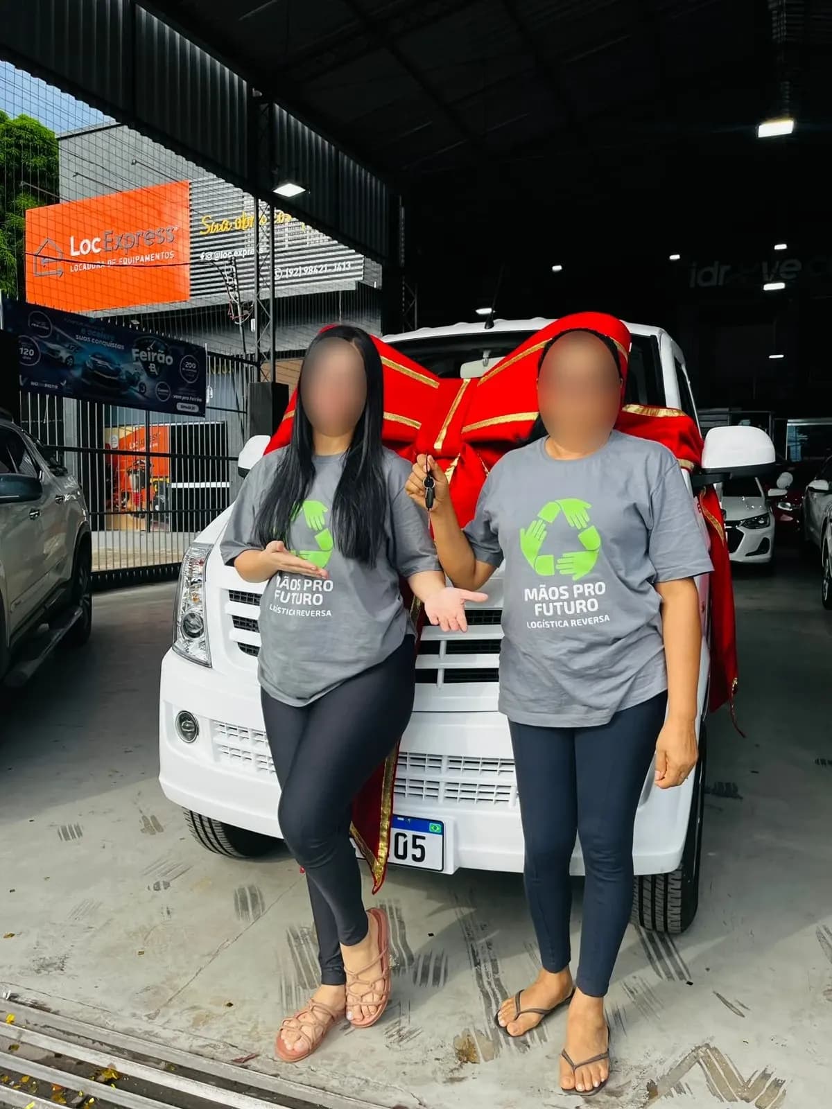 Duas clientes em frente ao Effa novo, com laço vermelho no capô