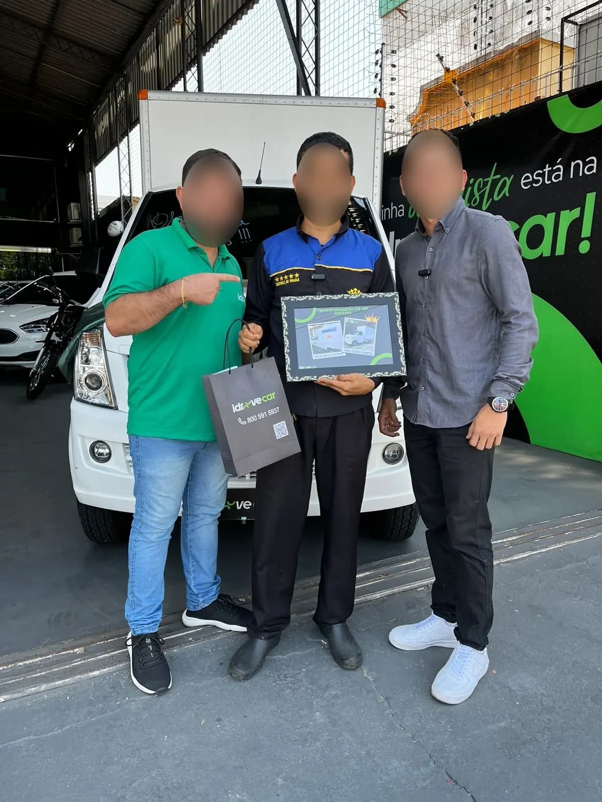 Cliente segura o quadro da entrega entre dois vendedores da Idroove