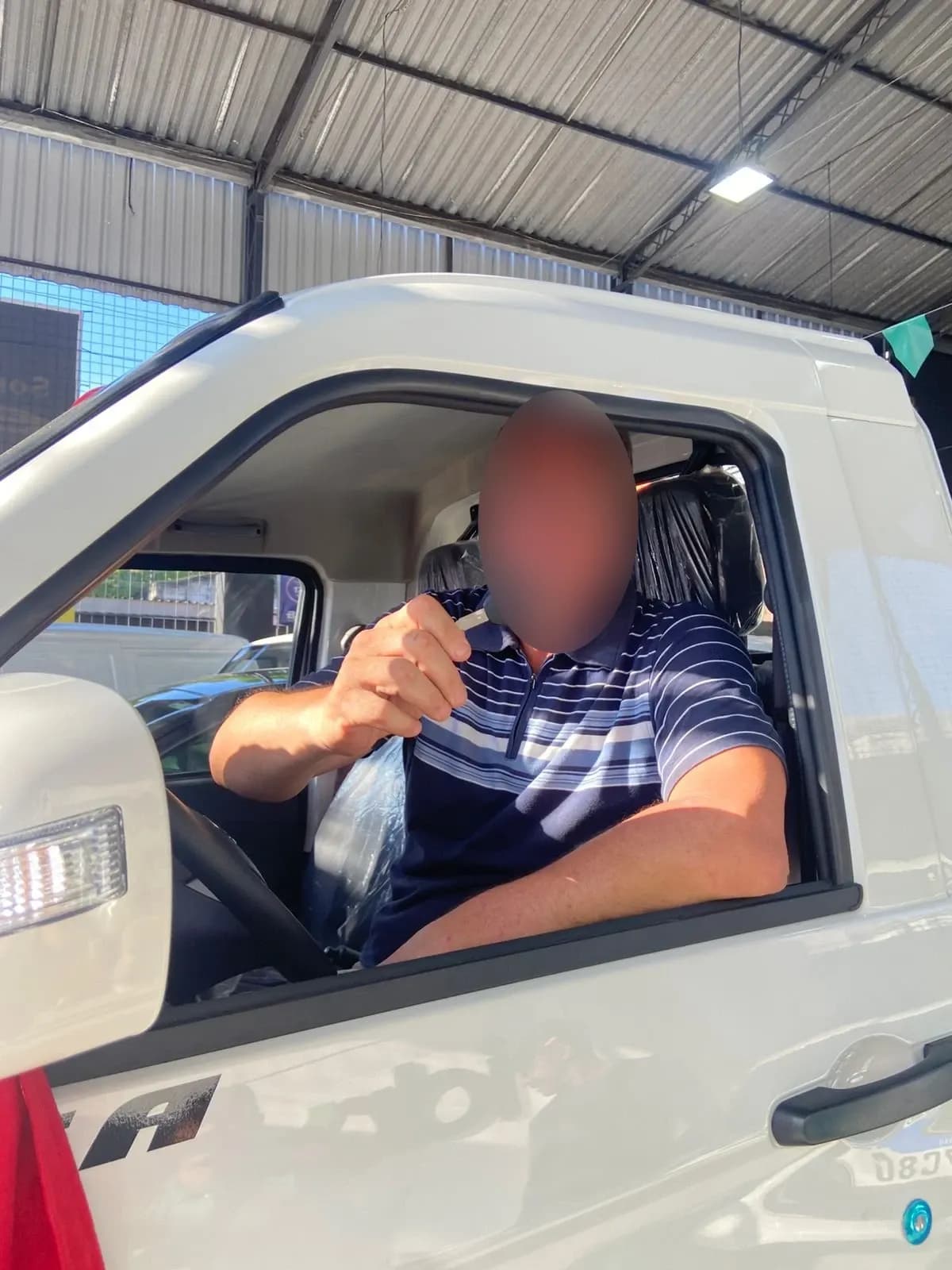 Cliente ao volante do Effa novo, mostrando a chave pela janela