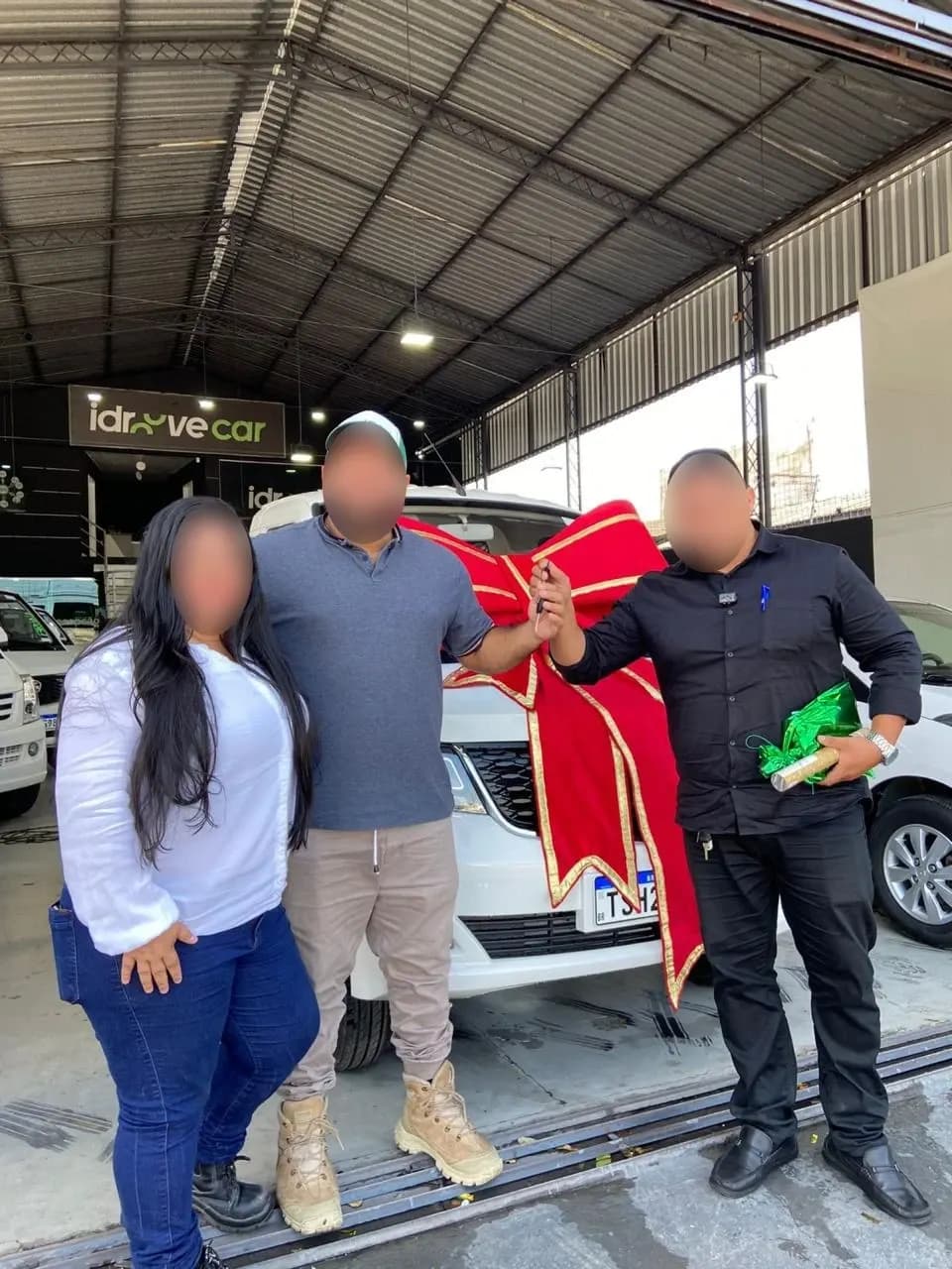 Três pessoas comemoram em frente ao Effa com laço vermelho